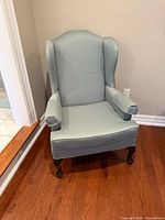 Front angled view of wingback chair showing upholstery and leg style