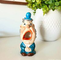 Front view of porcelain man ashtray showing open mouth, blue hat, jacket
