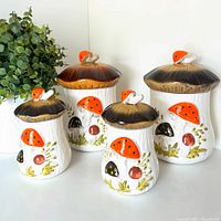 Front view of all four ceramic Merry Mushroom canisters with lids
