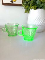 Two green uranium glass teacups side by side