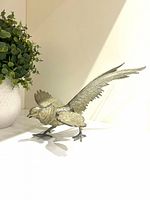 Profile view of brass pheasant figurine showing overall form and patina