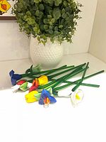 Group of nine glass flowers with green stems on counter
