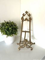 Front view of ornate brass easel showing scroll and shell detailing