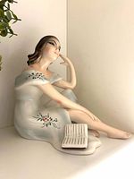 Full view of figurine showing seated pose, book, gown details