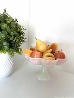Pedestal bowl with marble fruit next to plant