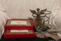 Three boxes of cards, two glass candle holders, stacked packaged ornaments