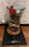 Full view of vase filled with assorted jewelry on scale