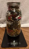 Full view of glass jar packed with assorted jewelry pieces