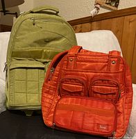Both Lug bags side by side: green rolling bag and orange tote