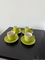 Four green espresso cups each on matching saucer