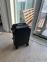 Front view of black hard-shell carry-on suitcase with handle retracted