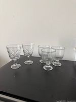 Five stemmed dessert glasses showing two patterns