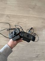 Two webcams held together showing overall condition and USB cables