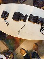 Three optical devices and their cases laid out on table