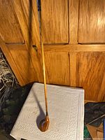 Full view of 40-inch hickory shafted driver leaning against cabinet