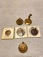 Group shot of all six medallions showing front sides and mounting conditions