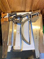 Five visible hand saws laid on table, showing handles and blades