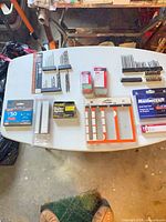 Full lot overview on table showing all packages of nails, staples, drill bits and driver bits