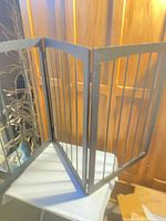 Full view of gate standing partially folded showing two panels and hinges