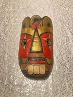 Front view of multicolor carved wood mask showing painted details and overall condition