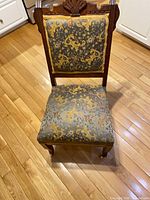 Front view showing carved crest, embroidered upholstery, seat and front legs