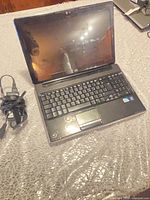 Laptop open showing keyboard, screen, touchpad, and charger