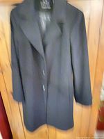 Full view of black Calvin Klein coat hanging to show overall style and condition