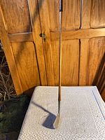 Full view of hickory-shafted 2 iron leaning against cabinet