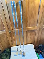 Full view of three wedges standing upright showing grips, shafts, clubheads