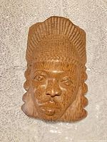 front view of teak wall mask showing carved facial features and headdress