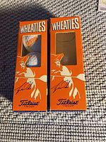 Two orange Wheaties display sleeves, one containing a golf ball