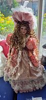 Full view of Cathay Collection porcelain doll in Victorian pink gown on stand