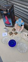 All items grouped on table including pool alarm box, glass dishes, figurine, platter, pyramids