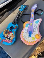 Both toy guitars side by side on surface