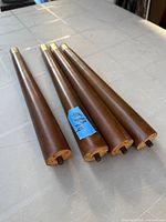 Four brown tapered wood screw-on legs lying on table