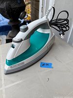 Left side view of Black+Decker steam iron showing teal water tank and soleplate