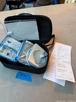 Carry case open showing controller, FlexTone pads, adapter, receipt