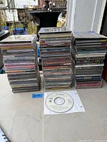 Overview of two tall stacks of jewel-case CDs plus one loose disc on table