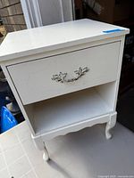 front view of white wood end table showing drawer, shelf, legs