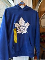 Front view of blue Toronto Maple Leafs hoodie displaying logo, pocket, hood and size tag