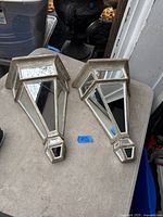 Top view of both mirrored wall brackets showing geometric mirrored panels and finish