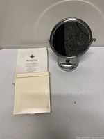 Artistry folding mirror closed beside chrome vanity mirror and instruction sheet