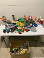 overview of entire mixed lot on table with vehicles, trains, track parts and structures