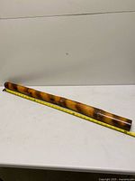 Full view of bamboo rain stick beside tape showing 38-inch length