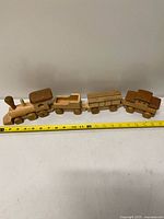 Entire four-car wooden train with tape measure showing length