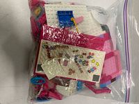 Full view of sealed bag showing loose pink and white building blocks and printed tile
