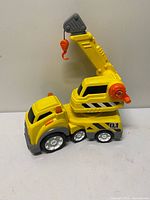 Side view of yellow plastic crane truck with arm folded