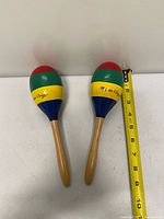Pair of wooden maracas beside tape for scale