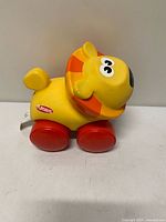 Left side view of Playskool rolling lion showing body, wheels, battery tab