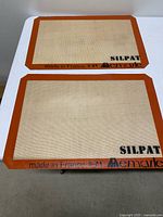 Two Silpat baking mats on table showing full size and logos